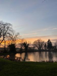 a sunset over a river with trees in the foreground at Beautiful Holiday Home - Lake view in York