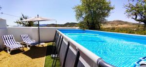 a swimming pool with two chairs and an umbrella at Immaculate Casa 2 bed 2 bath with pool Casa Oriana Oria Almeria in Oria