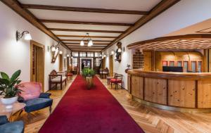 a lobby with a red carpet and chairs and a bar at Parkhotel Sole Paradiso in San Candido