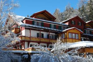 un grand bâtiment avec de la neige au sol dans l'établissement Parkhotel Sole Paradiso, à San Candido