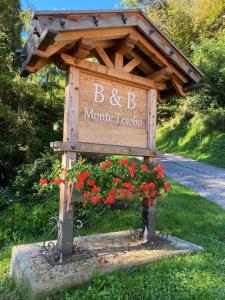 a sign for a morrisanical garden with red flowers at B&B Monte Tesobo in Roncegno