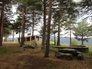 una cabaña en el bosque con árboles y rocas en Casa de la Cigüeña, en Candelario