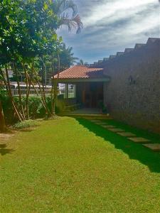 a house with a green lawn next to a building at Guarujá Apartment in Guarujá