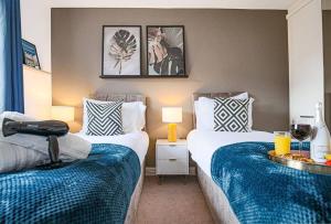 a bedroom with two beds with blue and white sheets at Bewdley House - 5 Bedroom 3.5 Bathroom House - Free Parking, Private Garden, Super-Fast Wifi and Smart TVs by Yoko Property in Milton Keynes