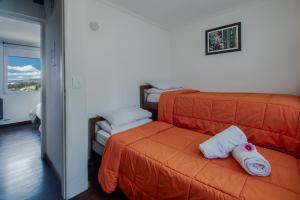 Un dormitorio con una cama naranja con toallas. en Departamento con vista al lago en Bariloche. en San Carlos de Bariloche