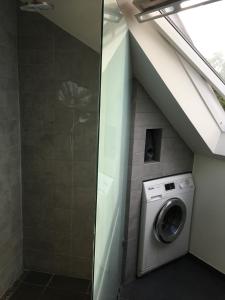 un lave-linge dans une salle de bains sous un toit dans l'établissement Quiet villa apartment close to everything, à Odense