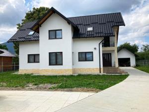 Biały dom z czarnym dachem w obiekcie Casa Hugo w mieście Kimpulung Mołdawski