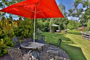 a table and chairs with a red umbrella at LLanwenarth Cottage a beautiful place to just be. in Abergavenny