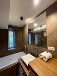y baño con lavabo, bañera y espejo. en MARMOT Mountain Apartment so saunou a hydromasážnou vaňou, en Nový Smokovec