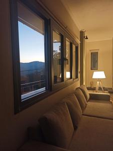 a couch sitting in a room with a window at Elatos Boutique MountainHouse in Karpenisi