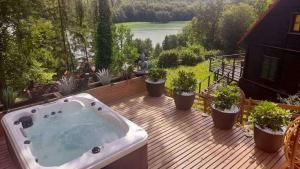 a hot tub on a wooden deck with potted plants at Mała Garda in Brodnica Dolna