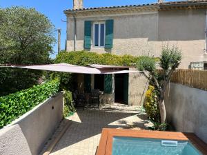 ein Haus mit einem Sonnenschirm und einem Pool in der Unterkunft La maison Mortisson in Saint-Rémy-de-Provence