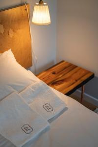 Cette chambre comprend un lit avec des draps blancs et une table en bois. dans l'établissement Apartament Różana 21, à Poznań