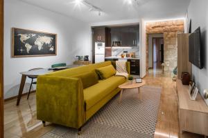 a living room with a yellow couch and a kitchen at Verde Biatia in Baeza