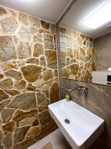 baño con lavabo y pared de piedra en MARMOT Mountain Apartment so saunou a hydromasážnou vaňou, en Nový Smokovec