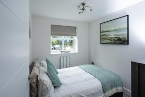 a white bedroom with a bed and a window at Quiet Luxury Countryside 2 Bedroom Detached Home in Shudy Camps