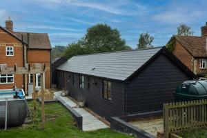 a black house with a deck in a yard at Quiet Luxury Countryside 2 Bedroom Detached Home in Shudy Camps