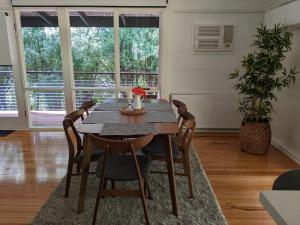 a dining room with a wooden table and chairs at Peaceful country home in a middle of a rainforest in Cockatoo