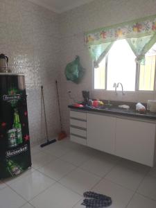 a kitchen with a refrigerator and a sink and a window at Casa de Praia com piscina in Mongaguá