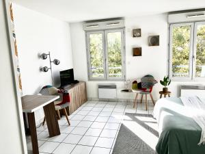 1 Schlafzimmer mit einem Bett, einem Schreibtisch und 2 Fenstern in der Unterkunft Bell Combe Studio - Proche Gare PartDieu in Lyon