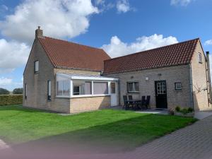 a large brick house with a grass yard at Vakantie-woning in Sint Kruis