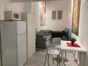 a kitchen with a white refrigerator and a table with chairs at Golondrinas de Malaga "Apartamentos con mucho Arte" y terraza solarium en coliving in Málaga