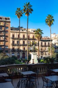 widok na budynek ze stołami i palmami w obiekcie Hotel Joli w mieście Palermo