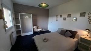 - une chambre avec un lit blanc et une chaise dans l'établissement Adorable studio avec entrée indépendante, à Dijon