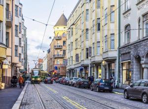 un tranvía en una calle de la ciudad con coches y edificios en Design District Area - Compact Apartment Helsinki Center, en Helsinki