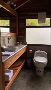 ein Bad mit einem Waschbecken und einem WC in der Unterkunft Zafiro Boutique Hotel in Mindo