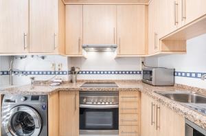 a kitchen with wooden cabinets and a washer and dryer at Paraiso Lido Sea Views 1-D Levante Beach in Benidorm