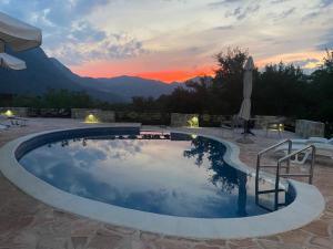 une grande piscine avec un coucher de soleil en arrière-plan dans l'établissement Vila Pegaz, à Virpazar
