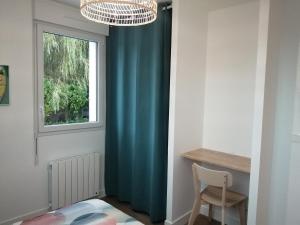 Habitación con cortina azul y ventana en Appartement Zen au Cœur du Cotentin, en Valognes