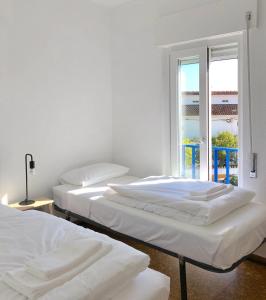 three beds in a room with a window at Sunshine Patio Getaway in Vila Nova de Milfontes