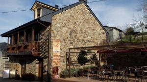 a brick building with a balcony and tables and chairs at Hostal Rural La Casa del Peregrino in El Acebo de San Miguel