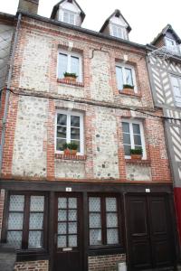 un antiguo edificio de ladrillo con ventanas y macetas en Les Songes d'Héléna, en Honfleur