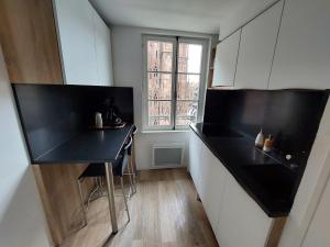 a kitchen with a black counter and a window at Les appartements Place de la Cathédrale in Strasbourg