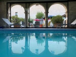 - une piscine avec 2 chaises et un parasol dans l'établissement Logis de La Roche - Niort - Chauray, à Chauray