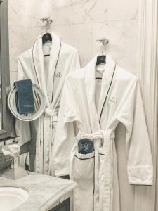 2 albornoces blancos en perchas en el baño en The Adelphi Hotel en Saratoga Springs