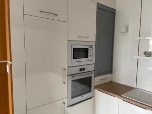 kuchnia z białymi szafkami i mikrofalówką w obiekcie Quelle-Apartman w Győr