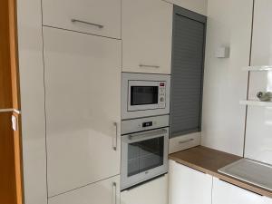 eine Küche mit weißen Schränken und einer Mikrowelle in der Unterkunft Quelle-Apartman in Győr