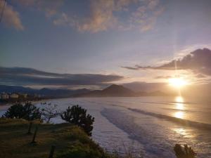 una vista del océano con la puesta de sol en Kitnet Ubatuba 2, en Ubatuba