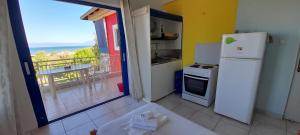 a kitchen with a white refrigerator and a balcony at Lakkopetra Beach Apartments in Lakkópetra