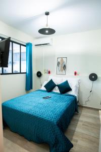 Schlafzimmer mit einem Bett mit blauer Decke in der Unterkunft Le Privilège appartement standing, piscine, terrasse, jardin, parking privé in Cayenne