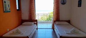 two beds in a room with a view of the ocean at Lakkopetra Beach Apartments in Lakkópetra