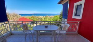 a white table and chairs on a balcony with the ocean at Lakkopetra Beach Apartments in Lakkópetra