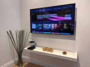 a flat screen tv hanging on a wall with two watches at Apartament Na Krzywym Kole in Kazimierz Dolny