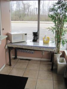 a counter with a microwave on a table next to a window at Royal Relax Inn in Fairmont City