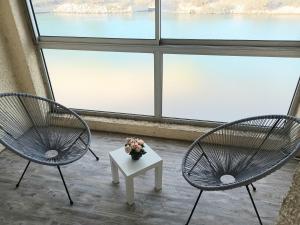 2 Stühle und ein Tisch vor einem Fenster in der Unterkunft Studio spacieux plage in Fos-sur-Mer