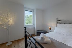 a white bedroom with a bed and a window at TAMLiving Ljubljana 2BR Center 3 Bridges Great View Kitchen in Ljubljana